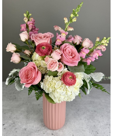 Pink floral arrangement with roses and seasonal blooms, presented in a coordinating vase.