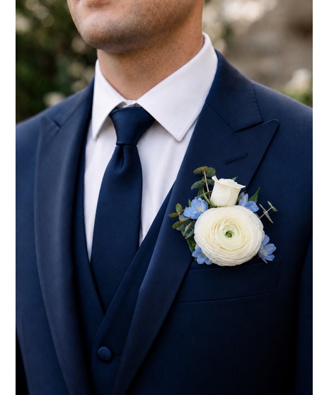 White and soft blue wedding boutonniere with greenery, available in groom, attendant, or floral pocket square style.