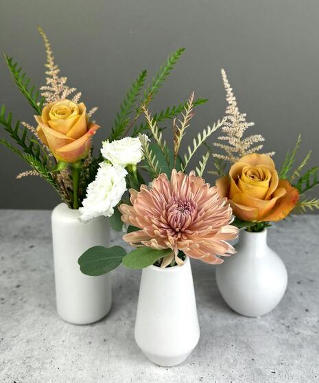 Boho arrangement with protea, roses, lisianthus, and textured blooms in blush, gold, ivory, and mauve tones.