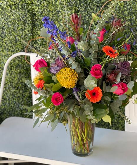 Colorful floral arrangement with unique blooms in bold pink, yellow, blue, and orange tones.