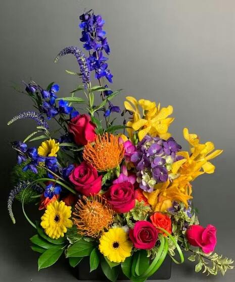 Colorful floral arrangement with unique blooms in bold pink, yellow, blue, and orange tones.