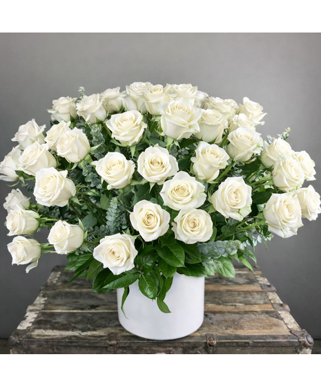 Long-stem assorted roses with seasonal accent flowers and greenery in a clear glass vase.