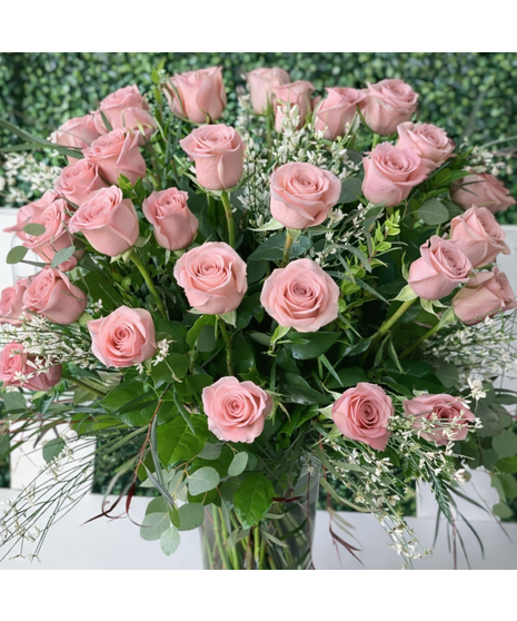 Long-stem assorted roses with seasonal accent flowers and greenery in a clear glass vase.