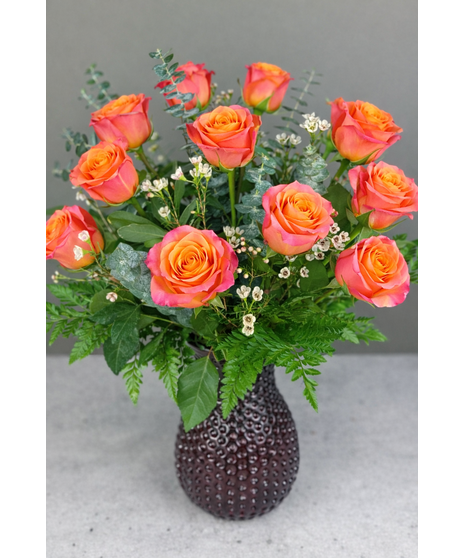 Long-stem assorted roses with seasonal accent flowers and greenery in a clear glass vase.