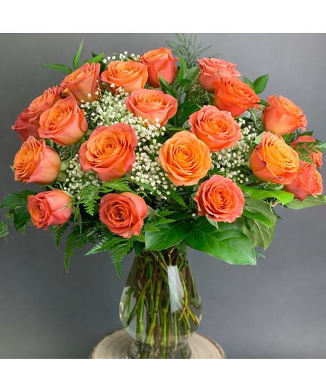 Long-stem assorted roses with seasonal accent flowers and greenery in a clear glass vase.