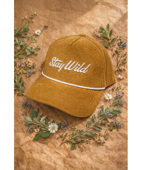 A corduroy hat with an embroidered ‘Stay Wild’ logo, white rope detail, and adjustable strap. Available in four colors.