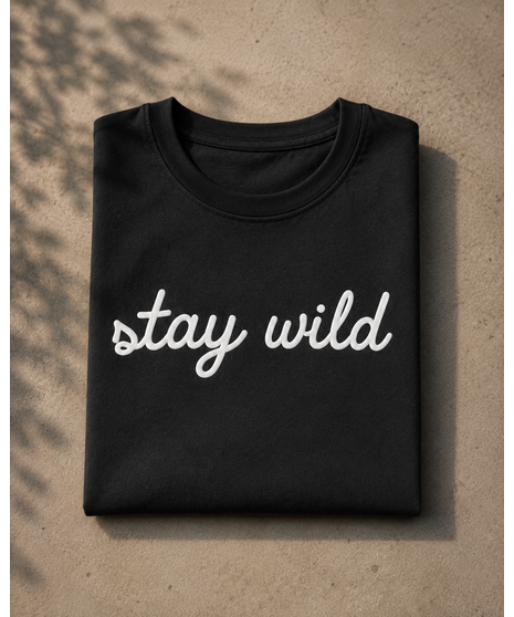 Black cotton t-shirt with raised white “stay wild” script lettering across the front in textured puff print.
