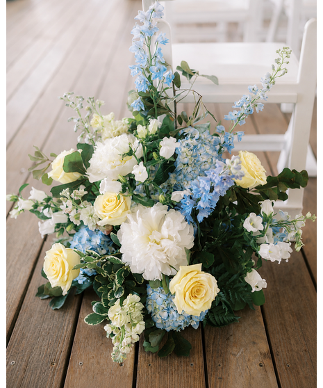 Wedding ceremony flowers featuring white, blue, and yellow blooms for arches, aisles, welcome signs, and floral installations.