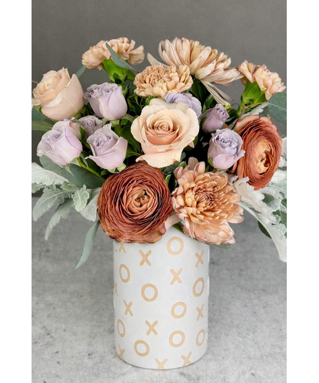 Vintage-inspired Valentine’s arrangement with blush, mauve, and pastel blooms in a clear glass vase.