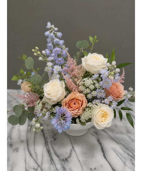Soft peach, ivory, blush, and dusty blue wedding accent flowers with romantic garden-inspired blooms and greenery.