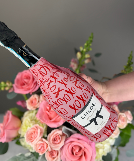 Wrapped tulip bouquet paired with wine or champagne and boxed dessert truffles arranged as a gift set.