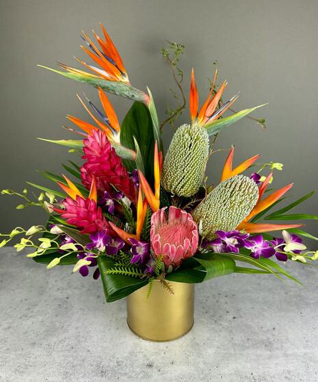 A stunning tropical floral arrangement featuring vibrant Birds of Paradise, lush orchids, and unique blooms arranged in a bespoke design.