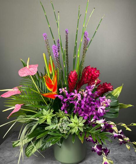 A stunning tropical floral arrangement featuring vibrant Birds of Paradise, lush orchids, and unique blooms arranged in a bespoke design.