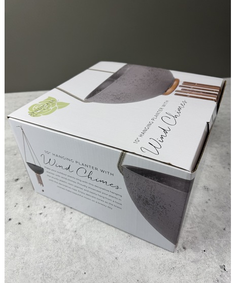 Hanging planter with built-in copper-toned wind chimes, rope hanger, and drainage plug in a charcoal or ivory finish.