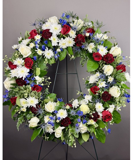 Circular standing wreath in red, white, and blue. Available in 4 sizes. Optional ribbon script for personalization. Displayed on an easel.