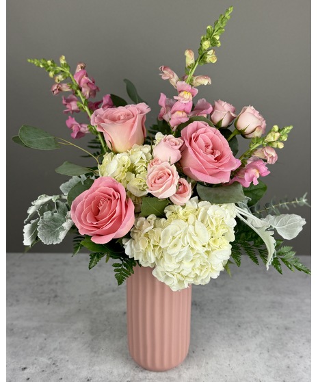 Pink floral arrangement with roses and seasonal blooms, presented in a coordinating vase.