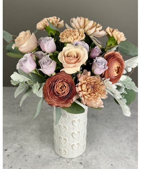 Vintage-inspired Valentine’s arrangement with blush, mauve, and pastel blooms in a clear glass vase.