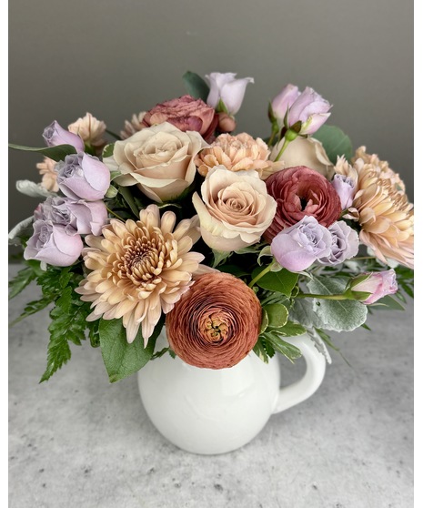 Vintage-inspired Valentine’s arrangement with blush, mauve, and pastel blooms in a clear glass vase.