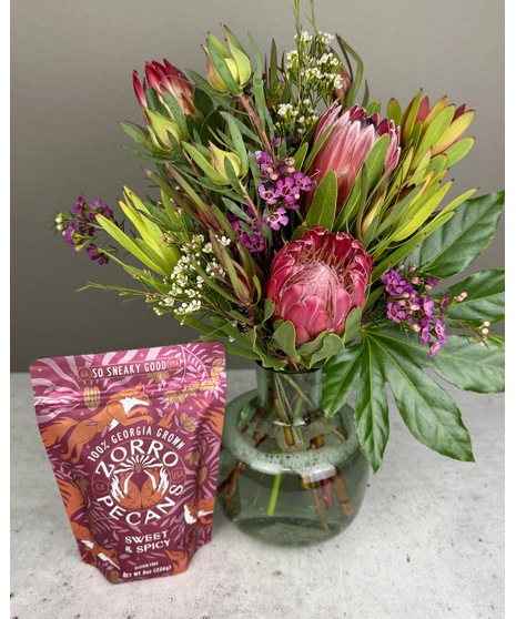 Modern floral arrangement with California-grown protea in a glass vase, paired with a bag of gourmet Zorro Pecans.