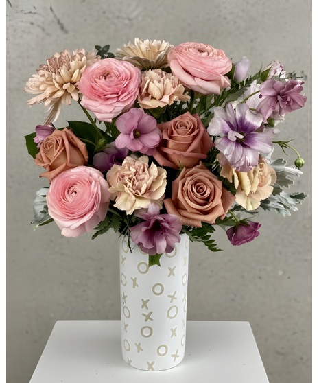Peach and blush floral arrangement in XOXO vase or pitcher with soft garden-style blooms.