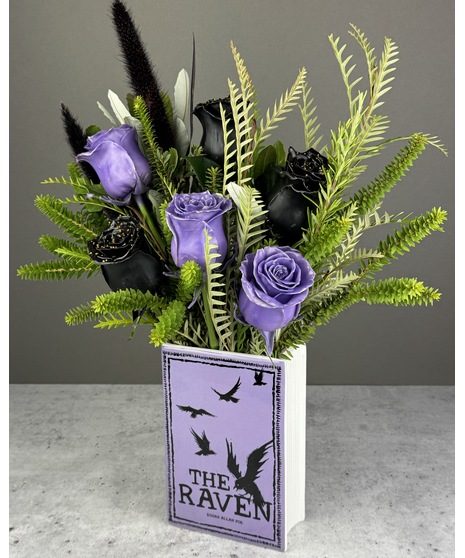 Arrangement of black and lavender wax-dipped, chocolate-scented roses in a book vase labeled “The Raven.” Non-edible.
