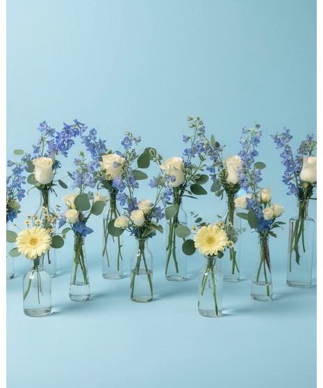 Wedding centerpieces featuring white, blue, and yellow blooms including bloom bottles, table centerpieces, and sweetheart table flowers.