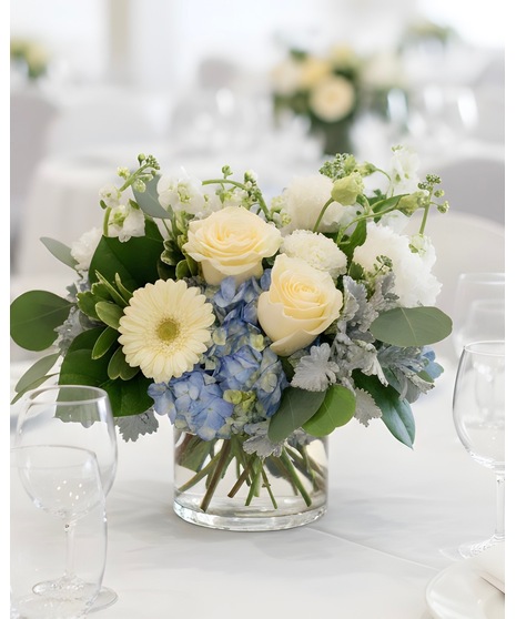 Wedding centerpieces featuring white, blue, and yellow blooms including bloom bottles, table centerpieces, and sweetheart table flowers.