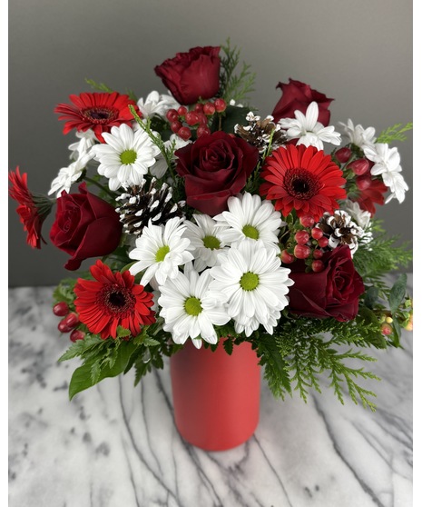 Red, white, and green Christmas arrangement with roses, daisies, berries, and pinecones.