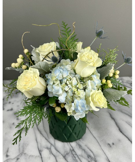 Winter blue and white arrangement with roses, hydrangea, and thistle in cool tones.