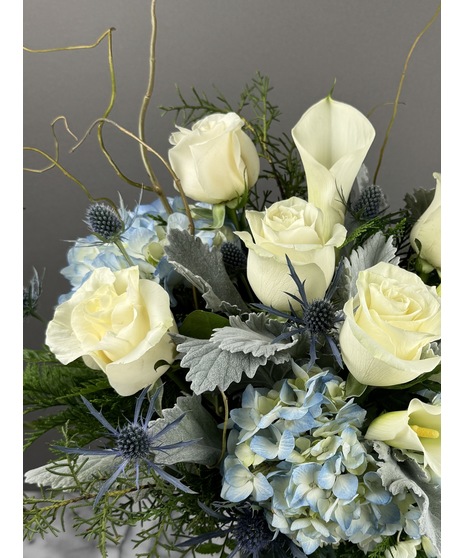 Winter blue and white arrangement with roses, hydrangea, and thistle in cool tones.