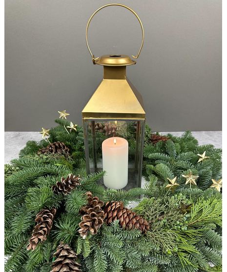 Gold lantern centerpiece with evergreens, pinecones, gold stars, and optional red roses.