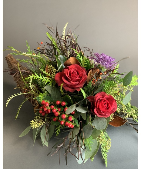Cornucopia centerpiece filled with layered greenery, textured foliage, and natural autumn elements.