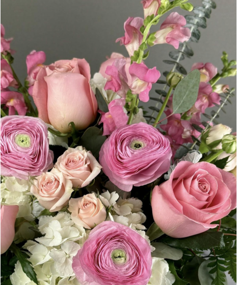Pink floral arrangement with roses and seasonal blooms, presented in a coordinating vase.