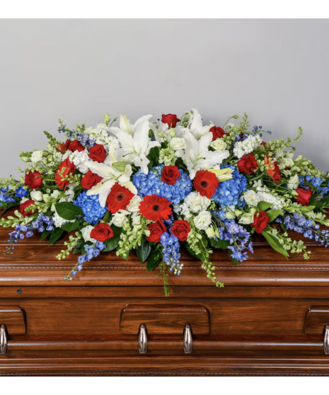A patriotic casket spray featuring fresh red, white, and blue flowers arranged to honor a proud American spirit.