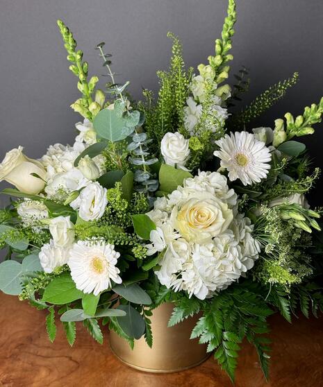 A designer’s choice arrangement featuring all white seasonal flowers in a vase, evoking peace and comfort.