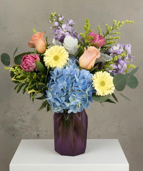 Pastel spring flower arrangement with roses, tulips, and seasonal blooms in a garden style.