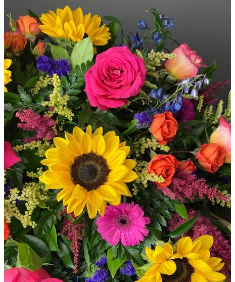 Bright colorful flower arrangement with sunflowers, roses, and mixed seasonal blooms.