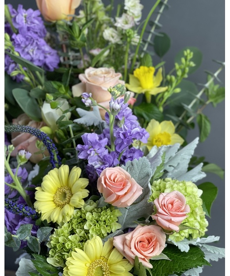 Pastel sympathy arrangement with peach roses, lavender blooms, yellow accents, and green hydrangea.