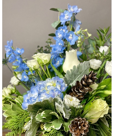 Blue and white floral arrangement with greenery and seasonal accents.