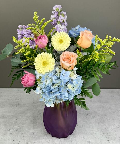 Pastel spring flower arrangement with roses, tulips, and seasonal blooms in a garden style.