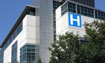 A modern multi-story hospital building, featuring a large blue 
