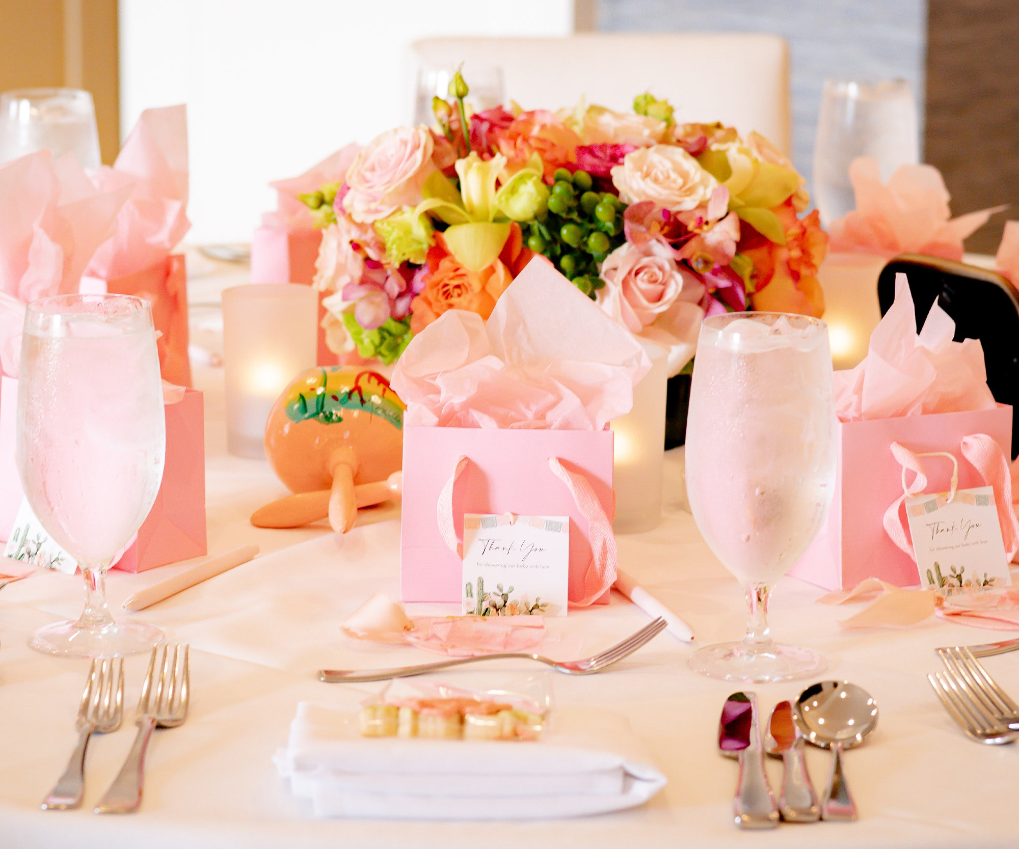 Floral baby shower tablescape with pink presents, pastel flowers, and place settings